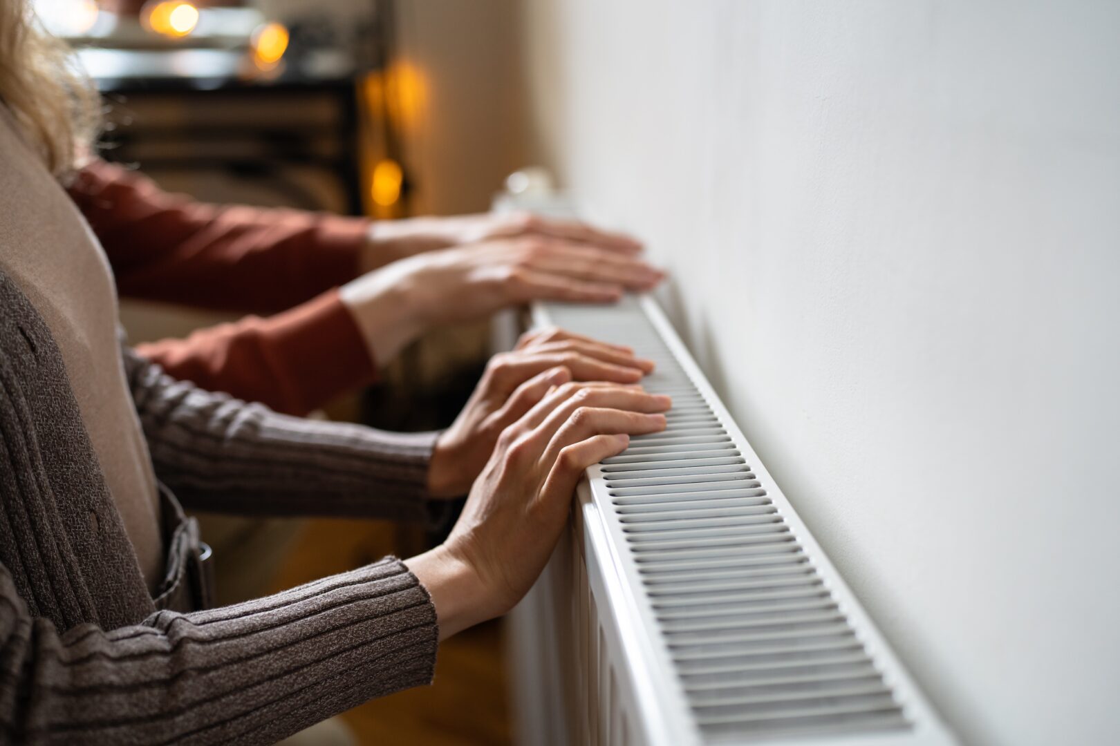 familycoupletouchingradiatorwithhandslivingincoldhome